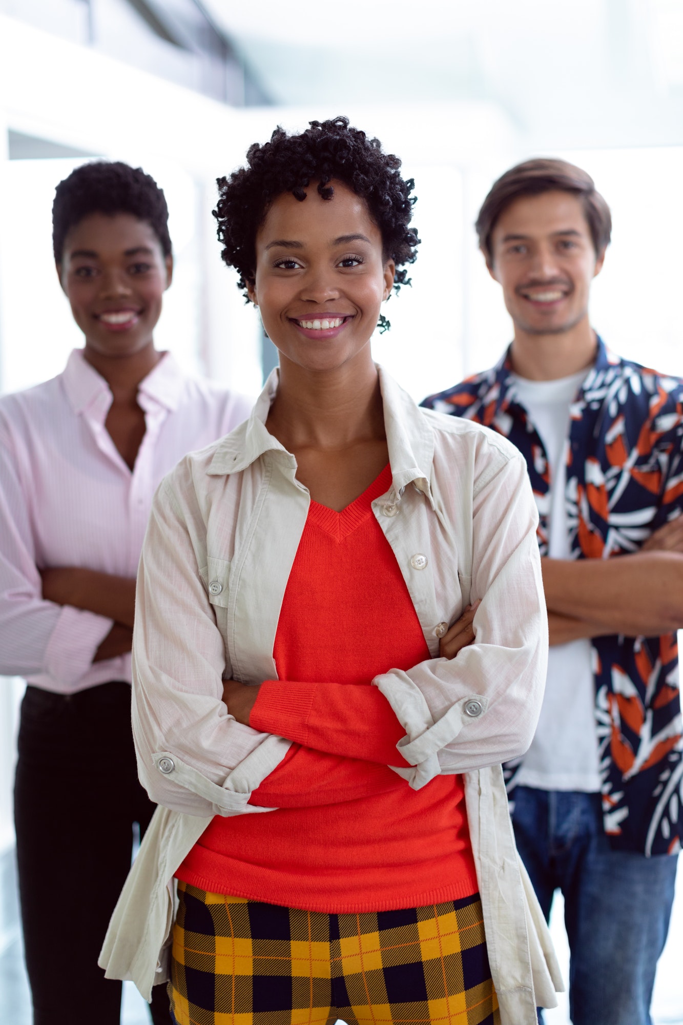 Front view of young diverse business people with arms crossed looking at camera in a modern office